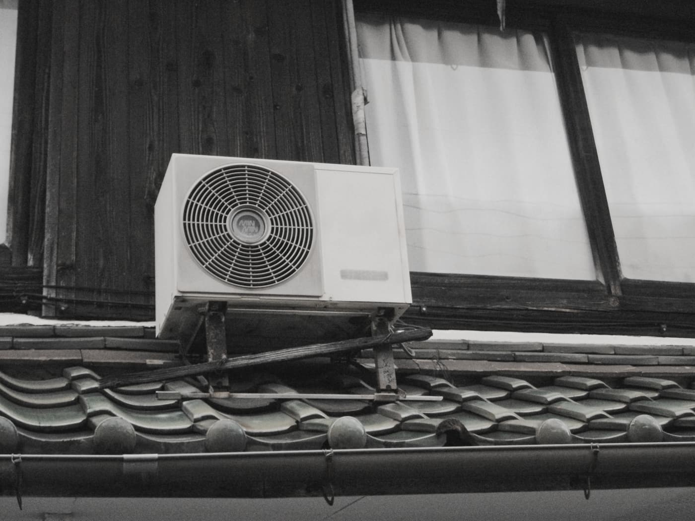 瓦屋根の上に設置されたエアコン室外機